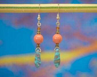 May include: A pair of dangle earrings with a peach-colored bead and a turquoise and gold patterned drop.