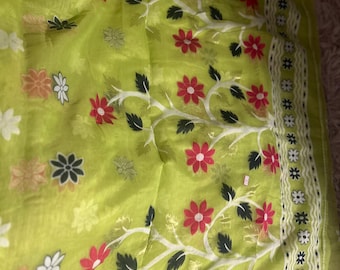 May include: A green saree with white and red floral patterns. The saree has a white border with black and white floral designs.