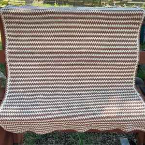 May include: A brown and white striped crocheted blanket with a scalloped edge.