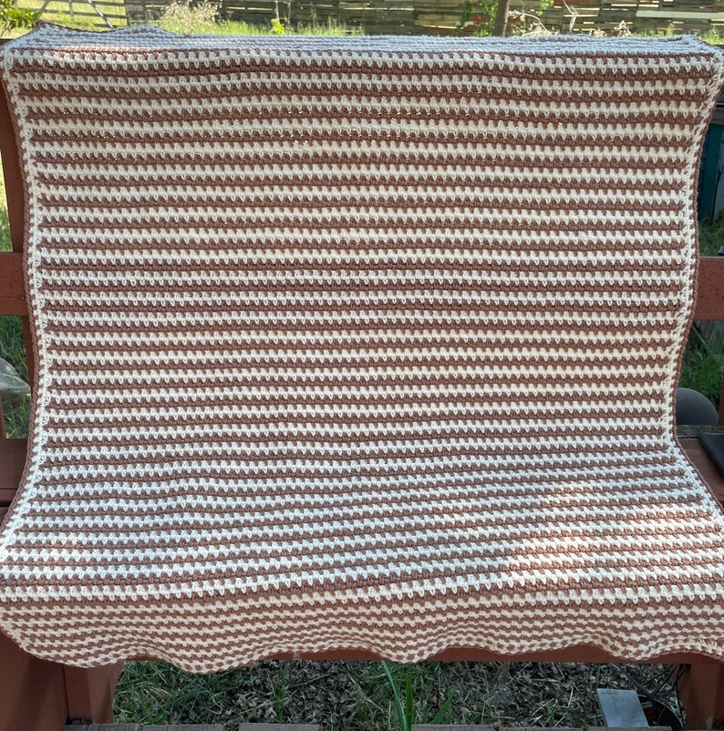 May include: A brown and white striped crocheted blanket with a scalloped edge.