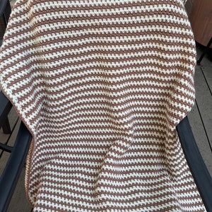 May include: A brown and white striped crocheted throw blanket.