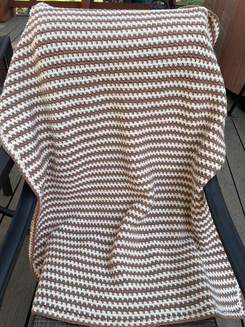 May include: A brown and white striped crocheted throw blanket.