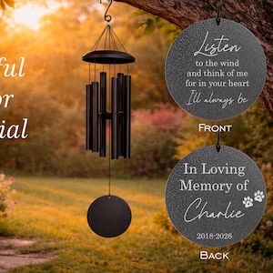 May include: Black outdoor memorial wind chimes hanging from a tree branch. The front of the memorial reads "Listen to the wind...I'll always be." The back reads "In Loving Memory of Charlie 2018-2026."