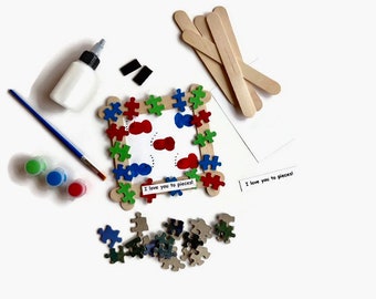 May include: A craft kit for making a picture frame. The kit includes wooden craft sticks, paint, glue, and puzzle pieces. The frame is decorated with colorful puzzle pieces and the words "I love you to pieces!"