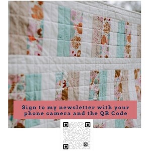 May include: A white quilt with a floral pattern in shades of pink, brown, and blue. The quilt is hanging on a clothesline. The text "Sign to my newsletter with your phone camera and the QR Code" is displayed on a pink banner below the quilt. A black and white QR code is displayed below the banner.