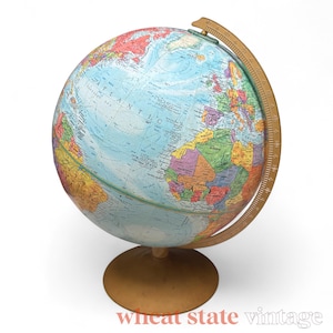 Może przedstawiać: Globus w stylu vintage z jasnobrązową podstawą i południkiem. Globus przedstawia szczegółową mapę z różnymi krajami i kontynentami w różnych kolorach, w tym niebieskie oceany oraz zielone, żółte i brązowe lądy. Widoczny jest napis "Atlantic".