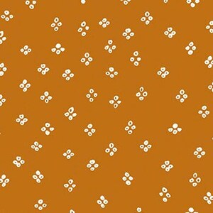 May include: A mustard yellow fabric with a white repeating pattern of small, simple flower shapes.