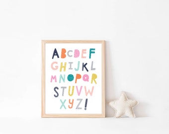 May include: A framed print of the alphabet in colorful, patterned letters. The letters are arranged in rows, with a small heart above the letter A. The frame is light wood.