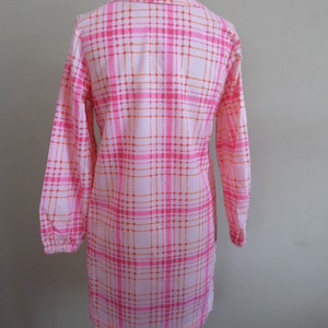 May include: A pink and orange plaid long-sleeved dress with a button-up collar.
