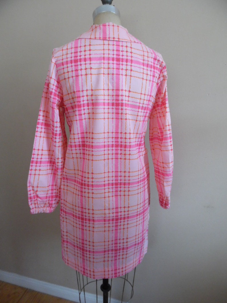 May include: A pink and orange plaid long-sleeved dress with a button-up collar.
