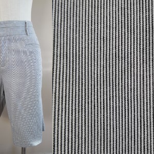 May include: A pair of light blue shorts with thin white stripes. The shorts have a waistband with belt loops and two front pockets.