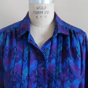 Könnte beinhalten: Ein langärmliges Hemd mit Knopfleiste und einem Muster in Blau und Lila. Das Hemd trägt ein Etikett mit der Aufschrift "WOLF FORM CO. N.Y.C."