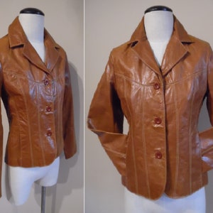 May include: A brown leather jacket with a button-up front and a collar. The jacket has a fitted silhouette and is lined with a brown fabric.