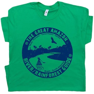 May include: A green t-shirt with a blue circle graphic on the front. The graphic says 'The Great Amazon River/Rainforest Guide' with the words 'Nauta - Porvenir - Tamschiyacu - Iquitos' and 'Brazil - South America' in smaller text.