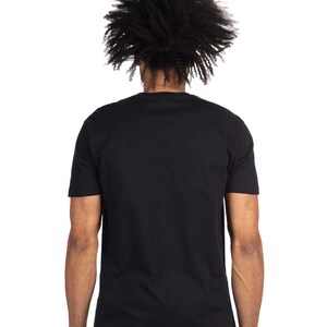 May include: A black crew neck t-shirt. The back view of the shirt is shown, with the person's head and shoulders visible. The person has dark, textured hair. The shirt is a solid black color and appears to be made of a soft material.