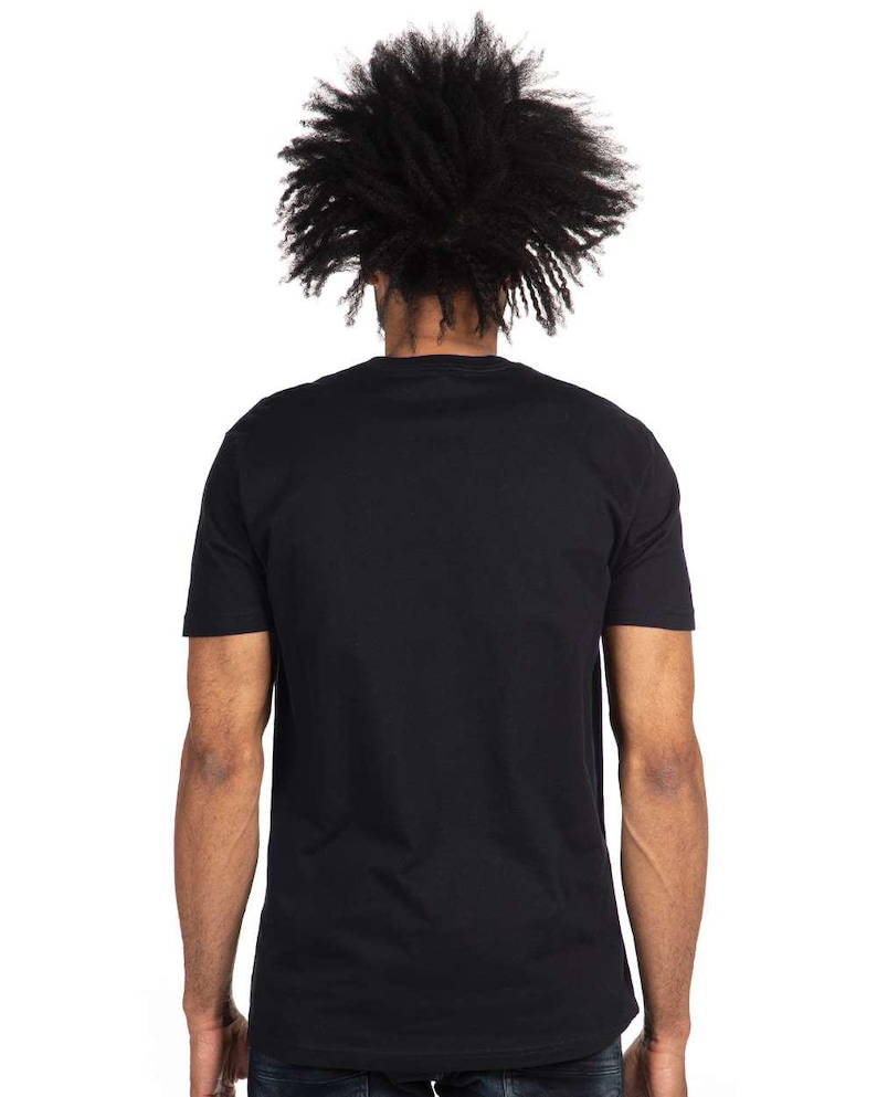 May include: A black crew neck t-shirt. The back view of the shirt is shown, with the person's head and shoulders visible. The person has dark, textured hair. The shirt is a solid black color and appears to be made of a soft material.