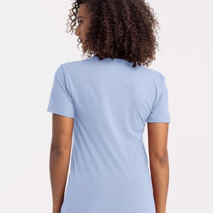 Puede incluir: Una camiseta azul claro de manga corta. La camiseta est&aacute; hecha de un material suave y tiene cuello redondo. La modelo lleva la camiseta, de espaldas a la c&aacute;mara. La camiseta es de color liso.