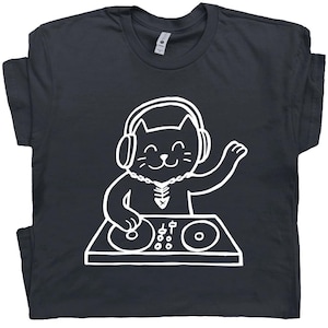 May include: Dark gray t-shirt featuring a white cartoon cat DJ wearing headphones and a necklace. The cat is smiling and has one paw raised. The cat is standing behind a DJ mixing board.