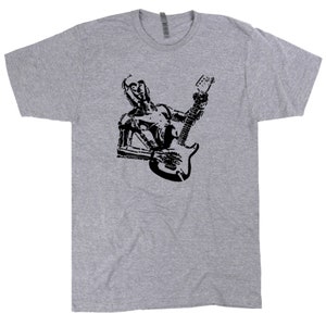 May include: A gray t-shirt with a black silhouette of a robot playing an electric guitar.