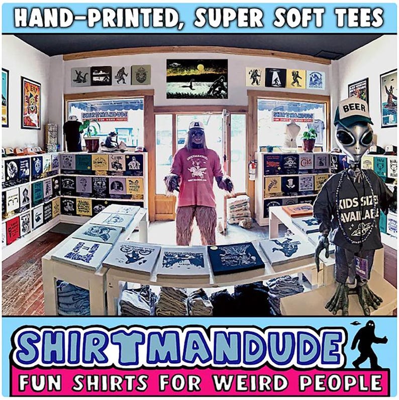 Op de afbeelding: Een winkel genaamd "Shirtmandu" met de slogan "Fun Shirts for Weird People" verkoopt handbedrukte, superzachte T-shirts. De winkel is versierd met een verscheidenheid aan T-shirts, posters en andere artikelen. Er zijn twee figuren in de winkel, een gekleed als Bigfoot en de andere als een alien.