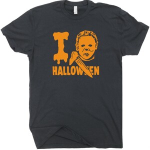 May include: A black t-shirt with an orange graphic of a masked figure holding a knife and the text "I  HALLOWEEN".