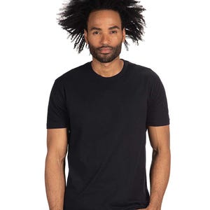 May include: A black crew neck t-shirt. The short-sleeved shirt is made of a soft material. The model has dark hair and a beard. The background is white.