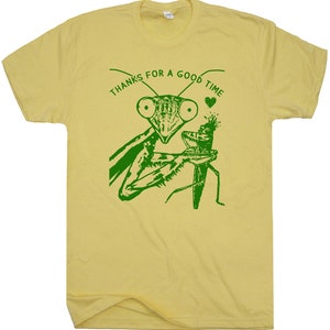 May include: A yellow t-shirt with a green print of a praying mantis holding a smaller insect. The text "THANKS FOR A GOOD TIME" is printed above the mantis.