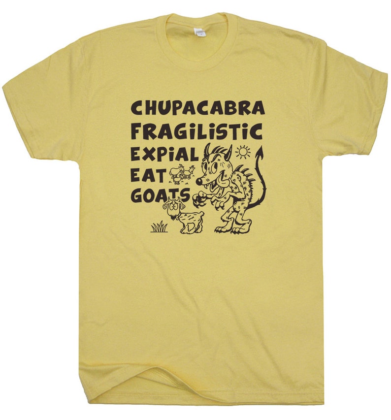 May include: Yellow t-shirt with a black graphic of a cartoon monster and goat, with the words "CHUPACABRA FRAGILISTIC EXPIAL EAT GOATS". The shirt is made of a soft material.