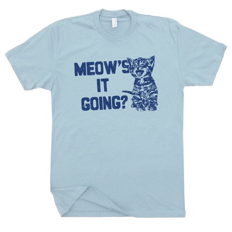 May include: Light blue t-shirt with a blue graphic of a kitten and the text "MEOW'S IT GOING?"