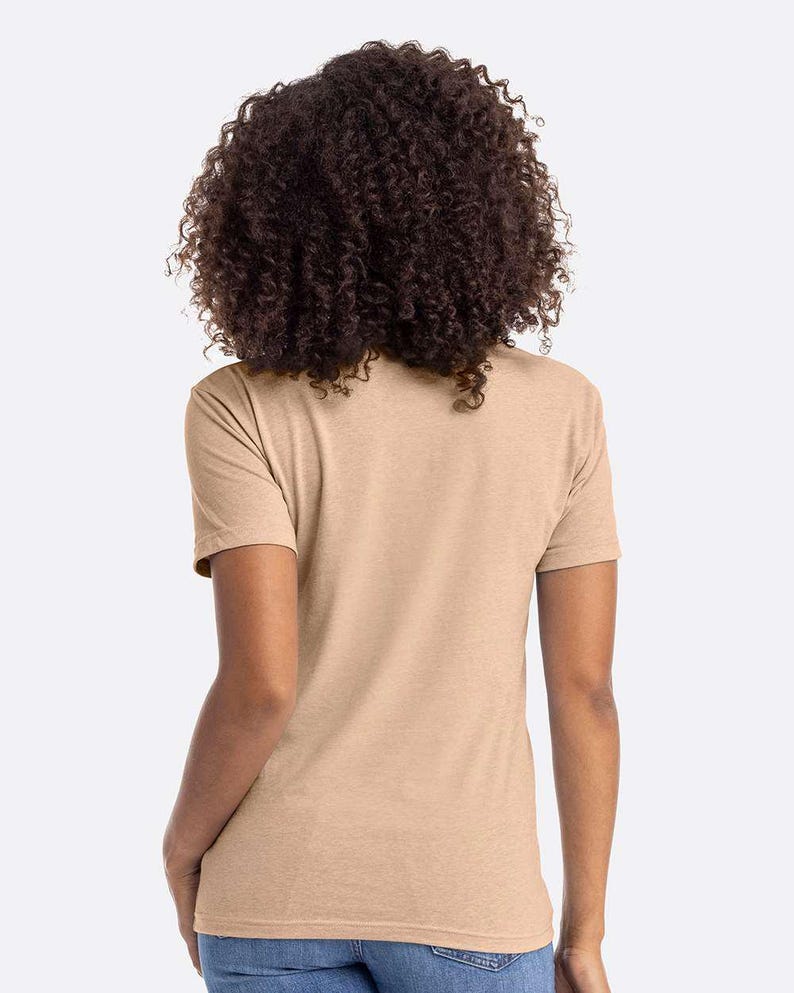 May include: A tan short-sleeve t-shirt. The shirt is made of a soft, heathered fabric. The model has dark curly hair.