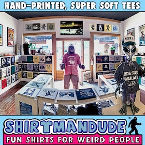 May include: A shop called "Shirtmandu" with the tagline "Fun Shirts for Weird People" is filled with colorful, hand-printed t-shirts. The shop is decorated with a variety of quirky items, including a large, furry creature wearing a pink shirt and a green alien holding a sign that says "Kids Sizes Available".