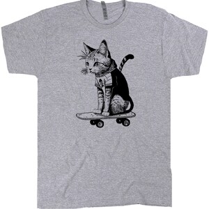 May include: A gray t-shirt with a black and white illustration of a cat skateboarding. The cat is wearing a striped shirt and has a bandana around its neck.