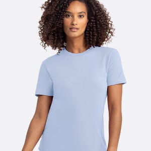 Puede incluir: Una camiseta azul claro con cuello redondo. La camiseta de manga corta est&aacute; hecha de un material suave. La modelo lleva la camiseta. La camiseta es de color liso y tiene un dise&ntilde;o cl&aacute;sico.