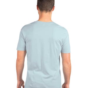 Puede incluir: Una camiseta azul claro con mangas cortas. Se ve la parte trasera de la camiseta, mostrando el cuello y el ajuste de la prenda. La camiseta est&aacute; hecha de un material suave.