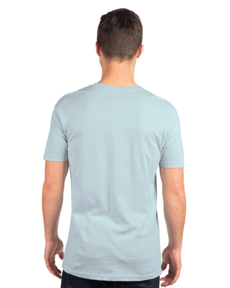 Puede incluir: Una camiseta azul claro con mangas cortas. Se ve la parte trasera de la camiseta, mostrando el cuello y el ajuste de la prenda. La camiseta est&aacute; hecha de un material suave.