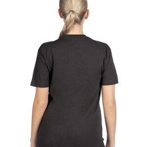 May include: A black short-sleeve t-shirt. The back of the shirt is visible, worn by a person with blonde hair pulled back in a ponytail. The shirt is a solid color and appears to be made of a soft material.