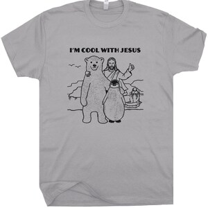 May include: A gray t-shirt with a black graphic of Jesus, a polar bear, a penguin, and a seal. The text "I'm Cool With Jesus" is printed on the shirt.