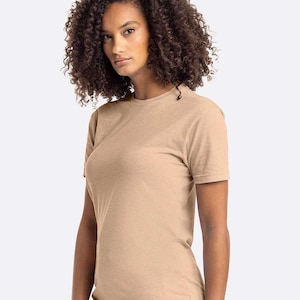 May include: A tan-colored, short-sleeved t-shirt. The shirt has a crew neck and a simple, classic design. The fabric appears to be a soft, heathered material. The model is wearing the shirt.