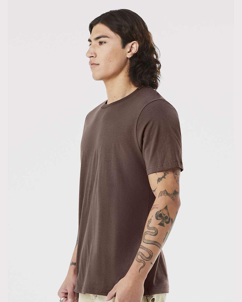 May include: A solid brown crew neck t-shirt. The short-sleeved shirt is made of a soft material. The model is wearing the shirt. The shirt is a basic wardrobe staple.