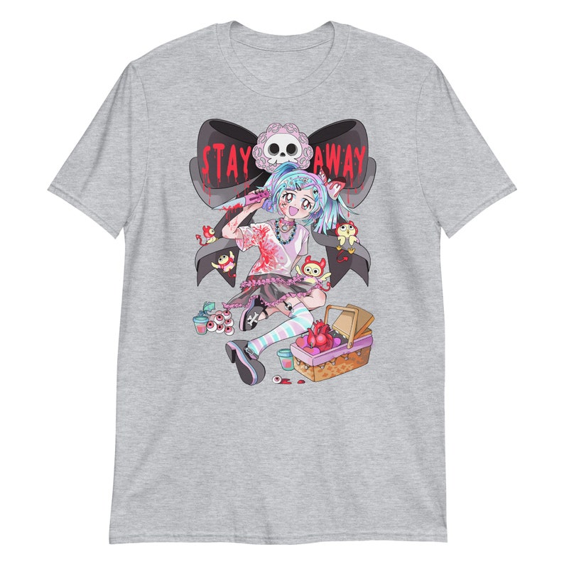 May include: A grey t-shirt with a graphic of a cartoon girl holding a knife. The girl is wearing a pink and black dress and has blue hair. The text "STAY AWAY" is written in red on a black ribbon behind her.