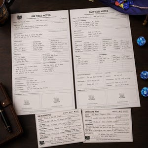 Puede incluir: Dos hojas de papel blanco para planificar sesiones GM Field Notes y dos tarjetas más pequeñas GM Scene Pod con texto impreso en negro y notas manuscritas. Los documentos incluyen secciones para detalles de sesión y seguimiento.