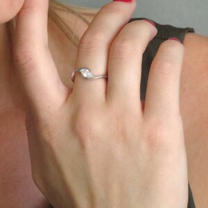 Op de afbeelding: Een zilveren ring met een enkele, heldere, marquise-vormige edelsteen gezet in een bladvormig ontwerp.