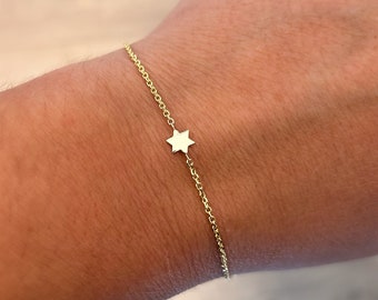 May include: A delicate gold chain bracelet with a small, flat, six-pointed star charm.