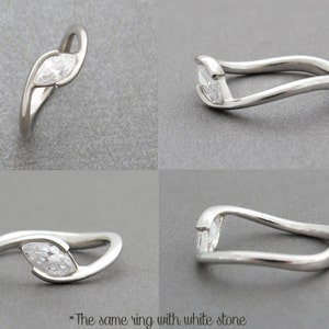 Op de afbeelding: Een zilveren ring met een marquise-vormige diamant gezet in een gebogen band.