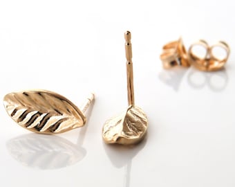 May include: A pair of gold leaf-shaped stud earrings. The earrings are made of a textured metal and have a simple post design.