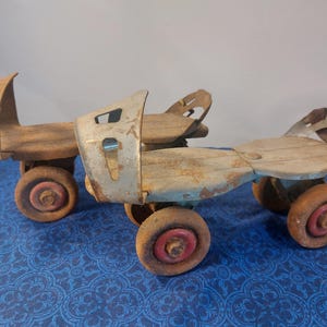 May include: A pair of vintage roller skates with wooden platforms and metal frames. The skates have four wheels each with red centers and show signs of wear and age. The metal frames are a light gray color.