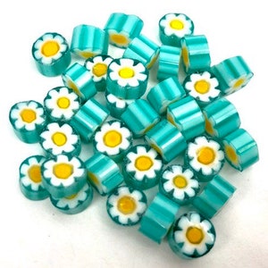 May include: A collection of turquoise and white glass beads with a daisy design. The beads are small and have a striped pattern.