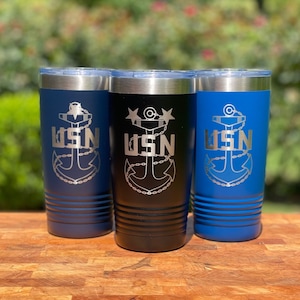 May include: Three stainless steel tumblers with a navy blue, black, and blue exterior. Each tumbler features a silver engraved anchor and the text "USN".