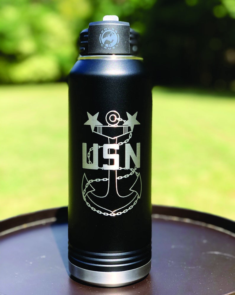 May include: Black stainless steel water bottle with a silver lid and a laser engraved design of a navy anchor with the text "USN" and two stars.