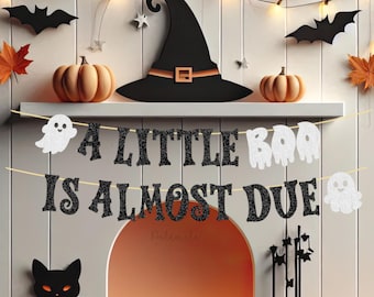Op de afbeelding: Halloween-thema schoorsteenmanteldecoratie met een zwarte heksenhoed, pompoenen, vleermuizen en een banner met de tekst "A LITTLE BOO IS ALMOST DUE". Een zwarte kat en kaarsen maken de feestelijke scène compleet.